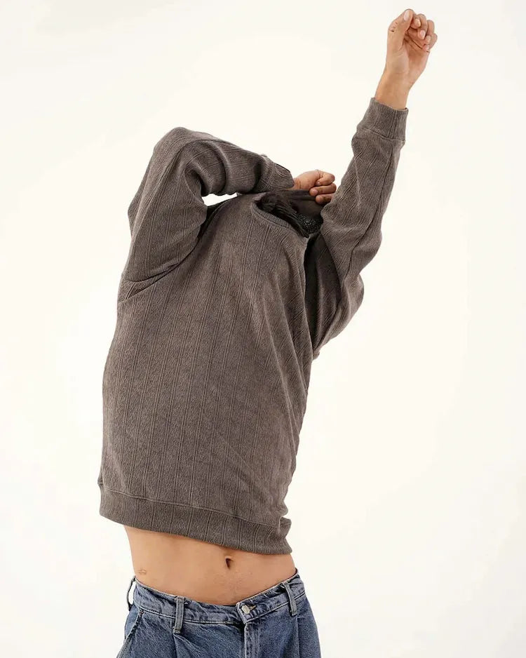 Person wearing a gray hoodie and blue jeans on a white background