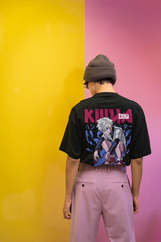 Person wearing a black t-shirt with graphic design and text, standing against a yellow and pink background.