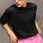 Person wearing a black turtleneck and pink pants with colorful sunglasses against a gray background