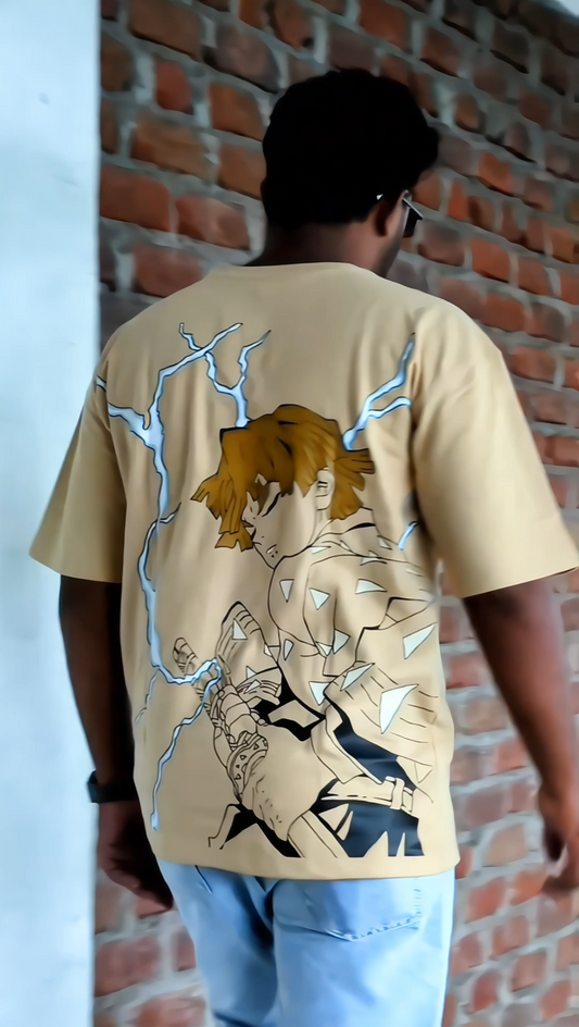 Person wearing a beige t-shirt with graphic design in front of a brick wall