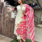Woman in a white outfit with a pink floral dupatta standing on grass.