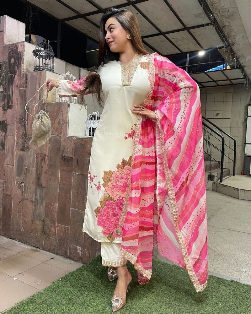 Woman in a white outfit with a pink floral dupatta standing on grass.